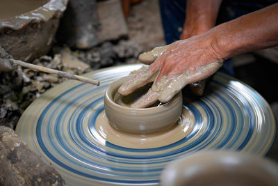 Cropped hands of man making pot in workshop