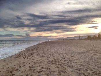 Scenic view of beach against cloudy sky