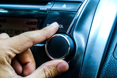 Close-up of hand adjusting knob in car