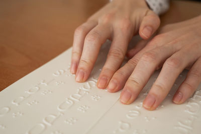 Cropped hands of woman reading braille alphabets