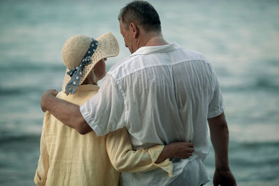 Rear view of friends standing against sea