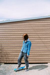 Young stylish woman wears sunglasses walks on the street with a skateboard