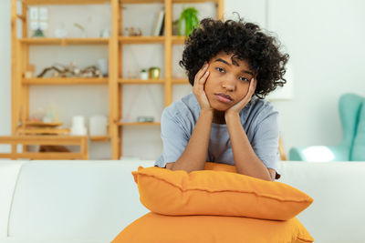 Portrait of young woman sitting on sofa at home