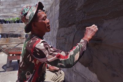 Side view of man standing against wall