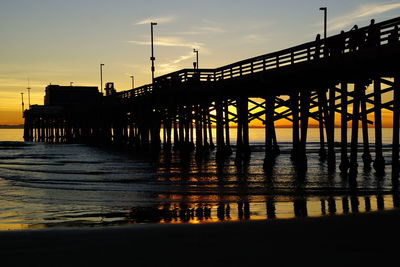 Silhouette pier over sea against sky during sunset