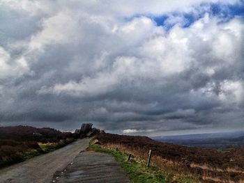 Empty road against cloudy sky