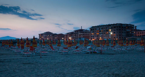 Panoramic view of beach against sky in city at dusk