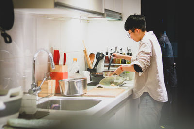 Side view of woman working in kitchen at home