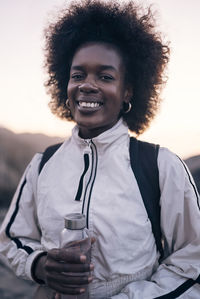 Portrait of smiling young woman holding water bottle