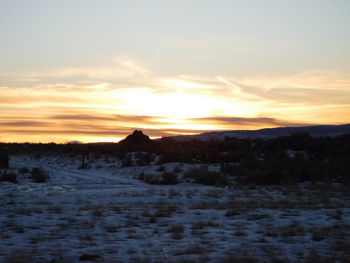 Scenic view of snow covered field against sky during sunset