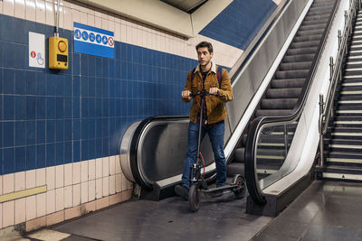 Man in stylish outfit walking with electric scooter in the underground