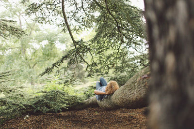 Woman lying on tree root