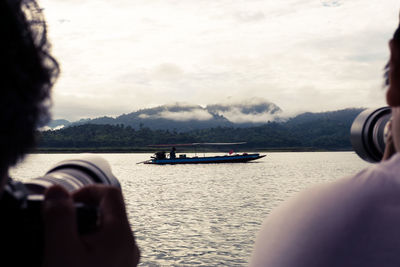 Close-up of hand on boat against sky