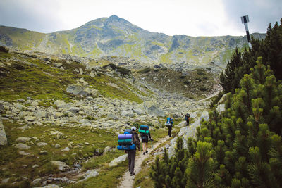 Rear view of people walking towards mountains