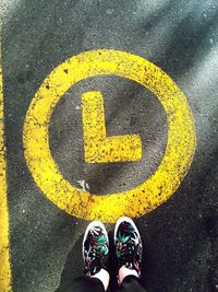 Low section of woman by letter l on road