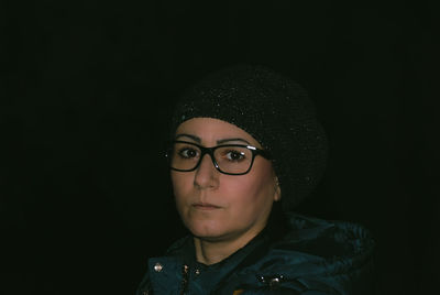Portrait of mature woman wearing knit hat against black background