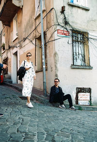 Full length of friends standing on street amidst buildings