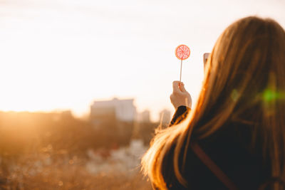 Teenage girl photographing lollipop with smart phone