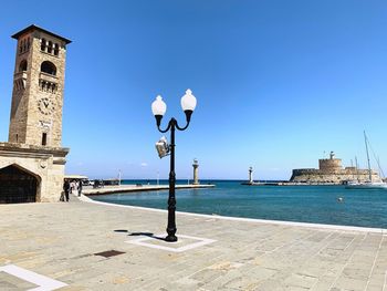 View of buildings by sea against clear blue sky