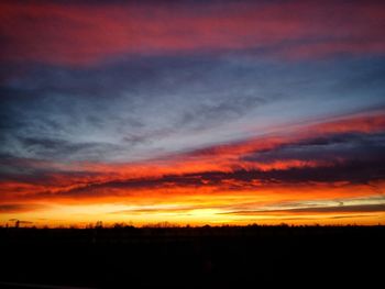 Silhouette landscape against dramatic sky during sunset
