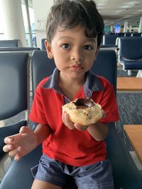 Cute boy eating food at airport terminal