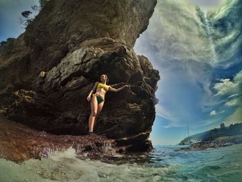 Rear view of woman standing on rocks at beach