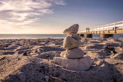 Rocks on beach against sky during sunset