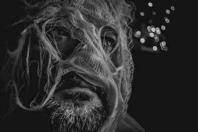 Close-up of man wearing mask against black background