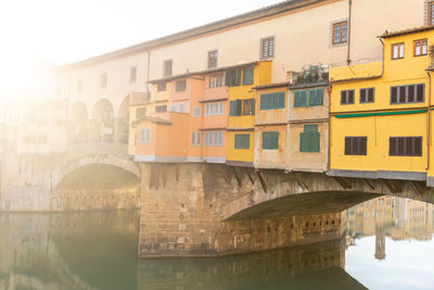 Arch bridge over river amidst buildings in city