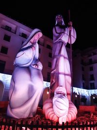 Low angle view of statue against illuminated building at night