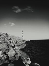 Lighthouse by sea against sky