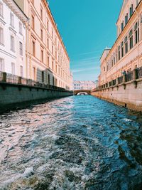 Arch bridge over river amidst buildings against sky in city