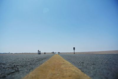Surface level of road against clear blue sky