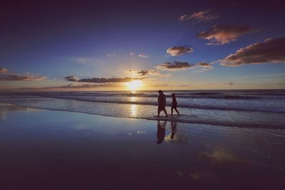 Silhouette of people walking on beach