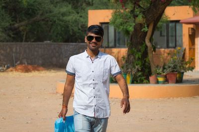 Portrait of young man wearing sunglasses standing outdoors