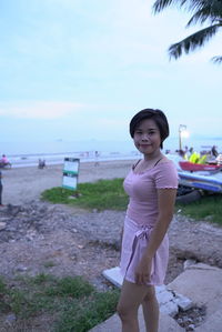 Portrait of woman standing on beach against sky