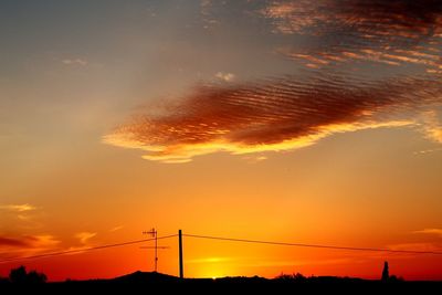 Silhouette electricity pylon against romantic sky at sunset