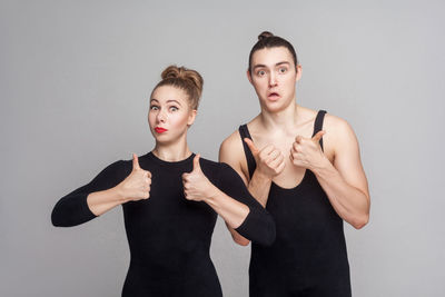 Portrait of couple gesturing against gray background