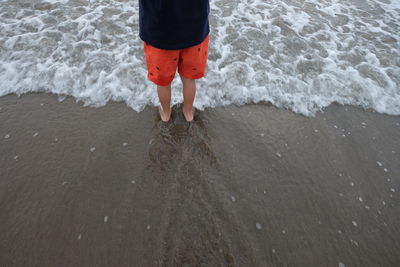 Low section of boy standing on beach