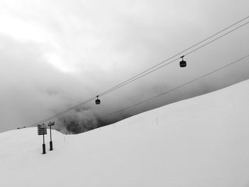 Low angle view of overhead ski lift against sky during winter