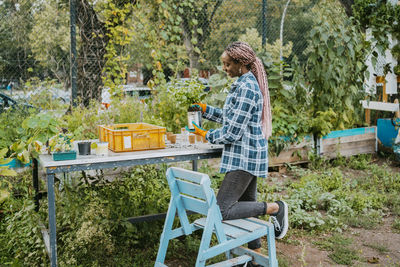 Young female volunteer planting at table in urban farm