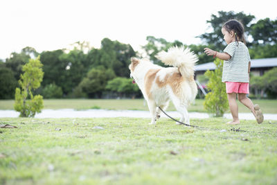 Side view of woman with dog running on field