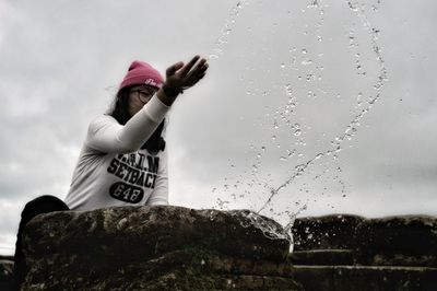 Portrait of woman standing by water against sky