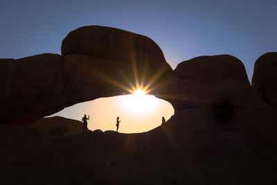 People standing on rock formation at spitzkoppe namibia during sunset