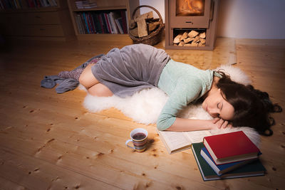 Young woman sleeping by books at home