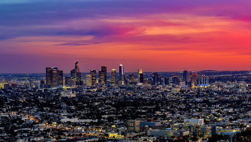 Illuminated cityscape against sky during sunset