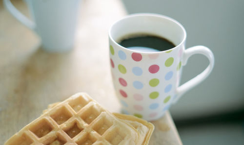 Close-up of coffee with waffles on table