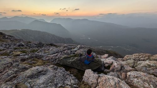 Man sitting on mountain during sunset