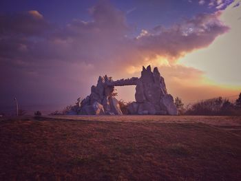 Built structure on field against sky at sunset