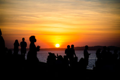 Silhouette people at beach during sunset